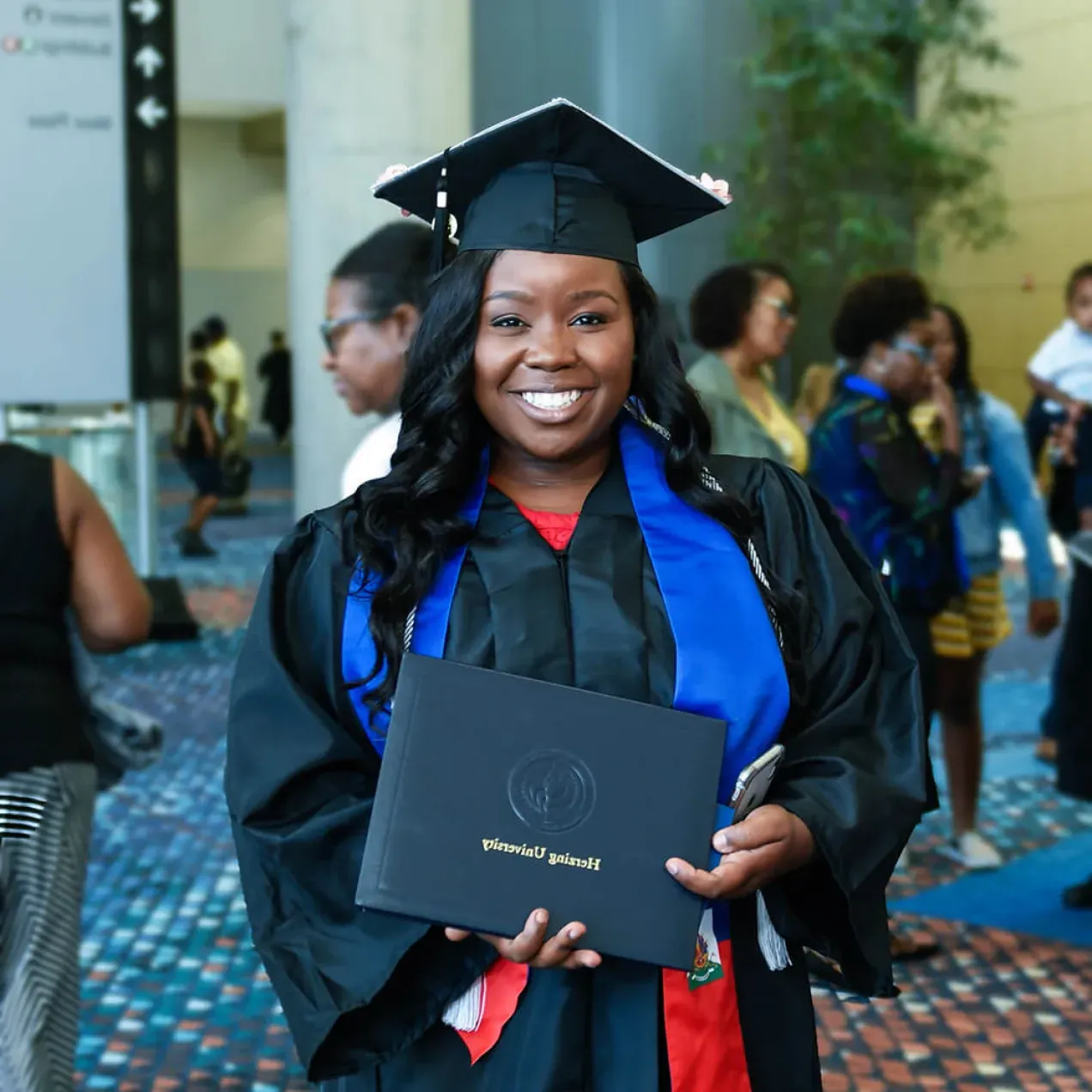 Herzing University Graduate Holding Diploma and Smiling